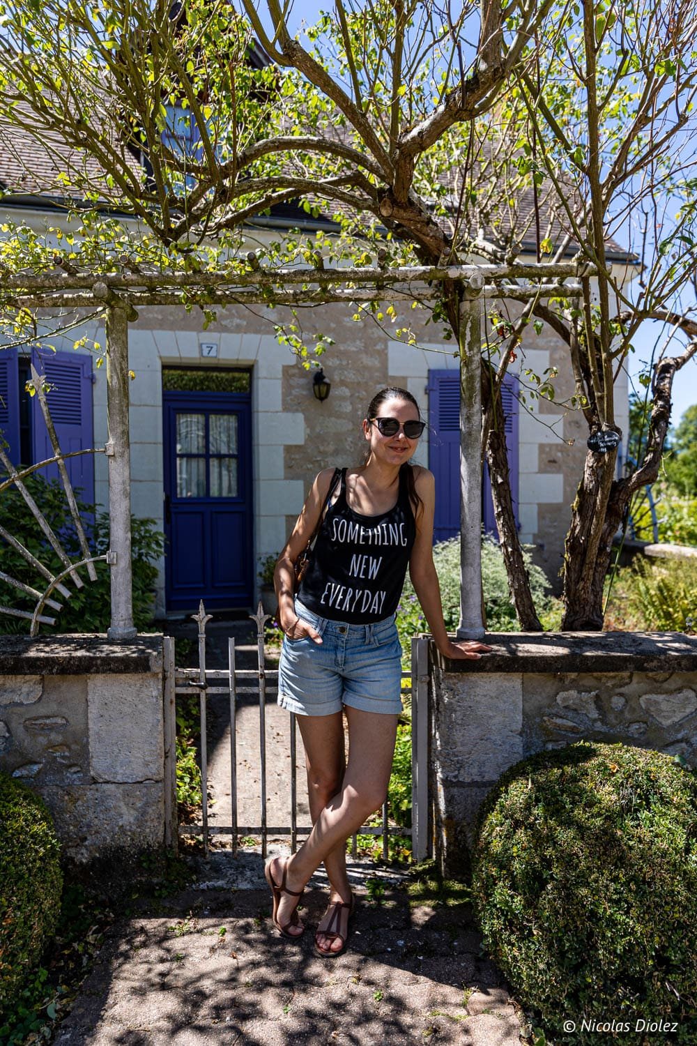 Femme devant une maison aux volets violets à Chédigny, près de Loches.