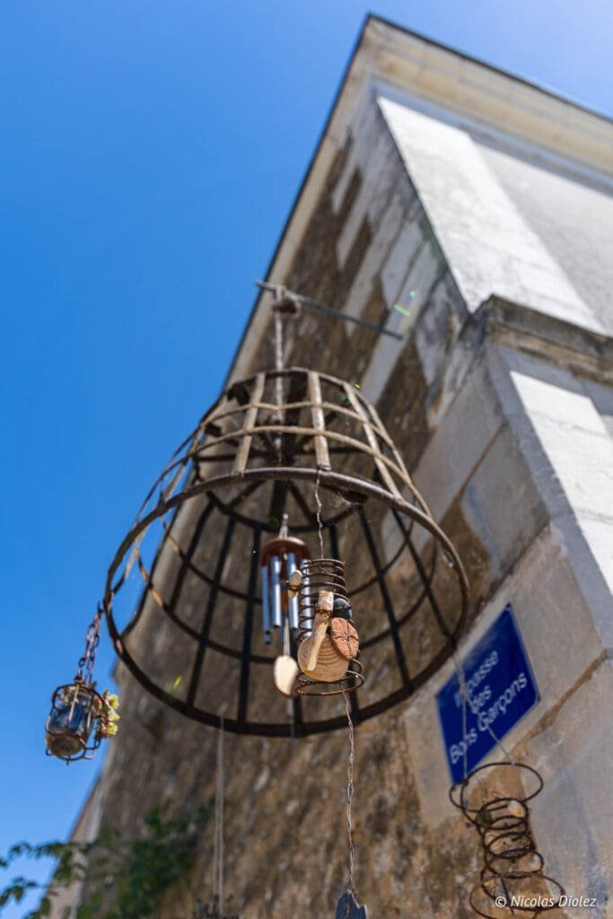 Wind chime hanging in front of an ancient wall near Impasse des Bons Garçons street.