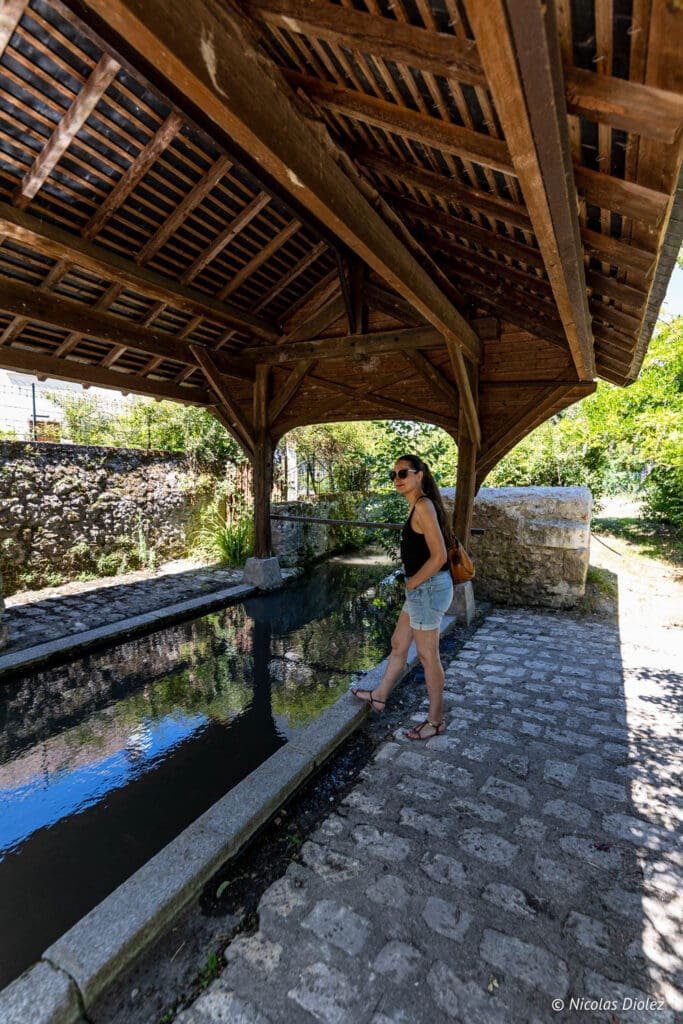 Lavoir couvert en bois à Chédigny, Sud Touraine, avec femme regardant l'eau.