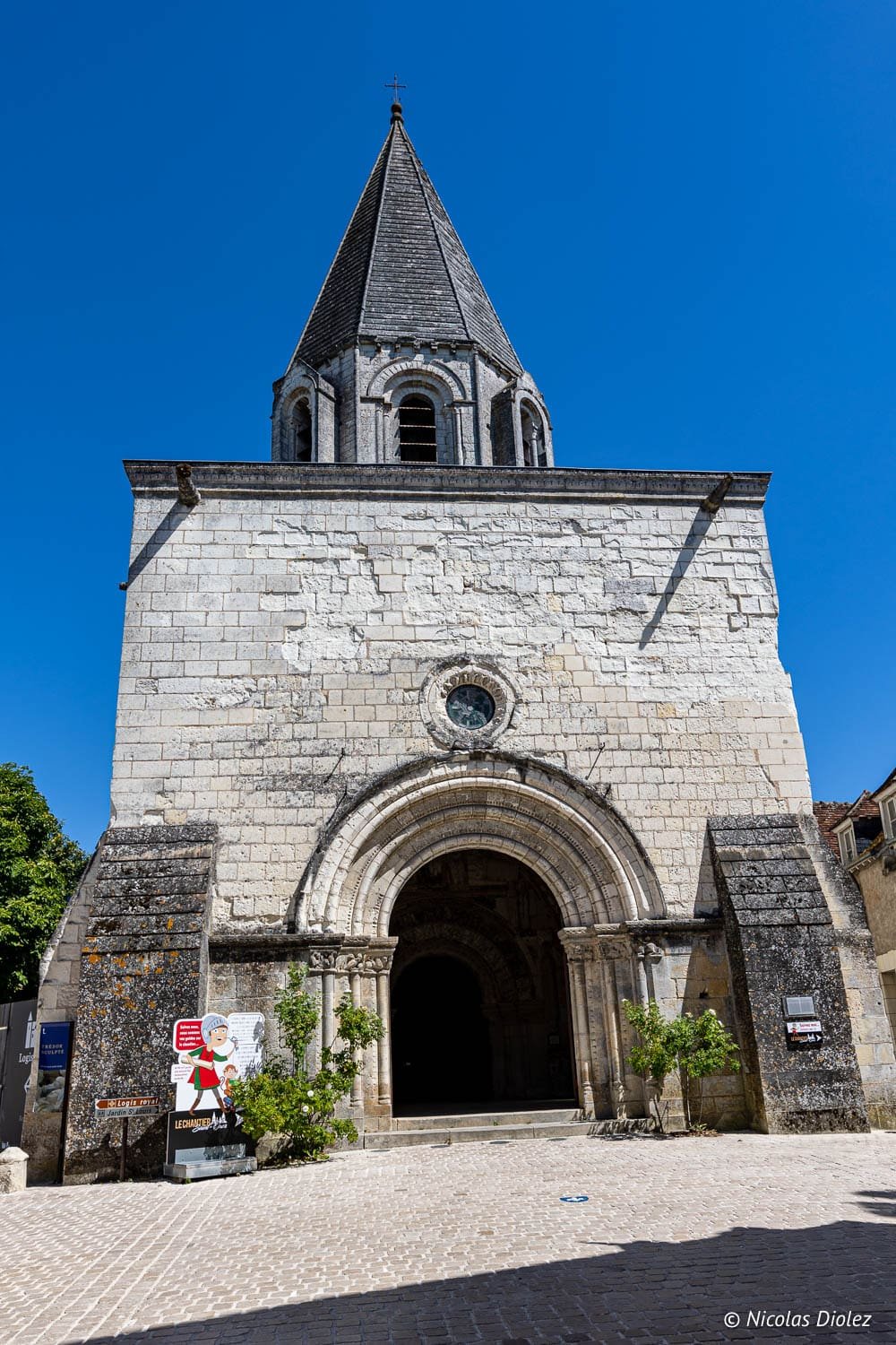 Façade de l'église Saint-Ours de Loches avec portail roman et toiture conique.