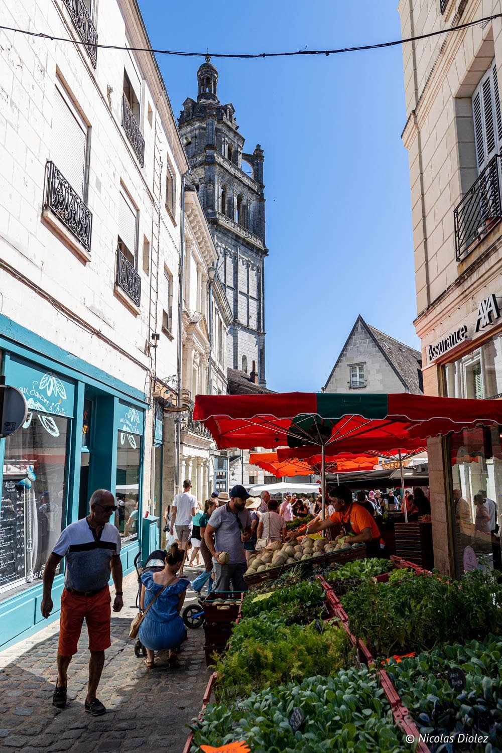 Marché de Loches avec vue sur le beffroi de l'église Saint-Ours par temps ensoleillé.