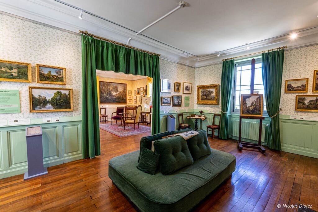 Intérieur du Musée Lansyer à Loches avec mobilier vert et tableaux exposés.