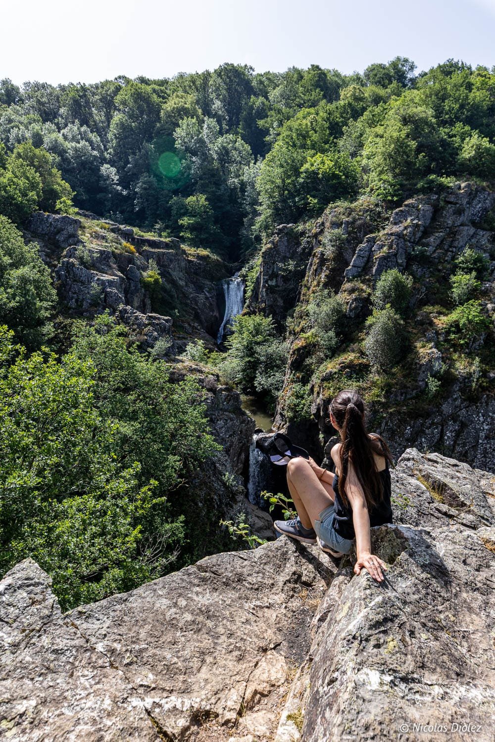 Randonneuse admirant les Cascades d'Arifat depuis un rocher escarpé.