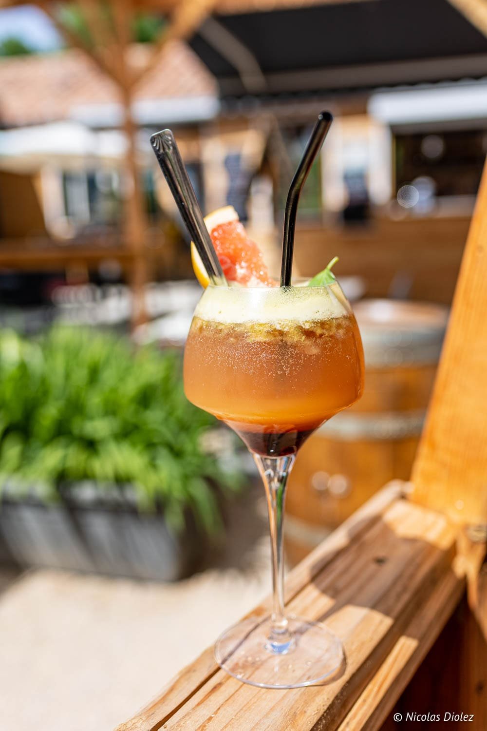 Cocktail brun avec pamplemousse et pailles sur une chaise en bois.