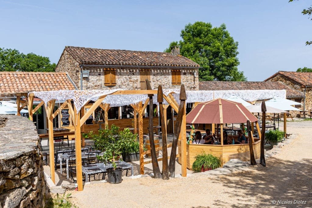 Terrasse extérieure en bois avec tables et maisons en pierre, Randonnée aux Cascades d'Arifat.