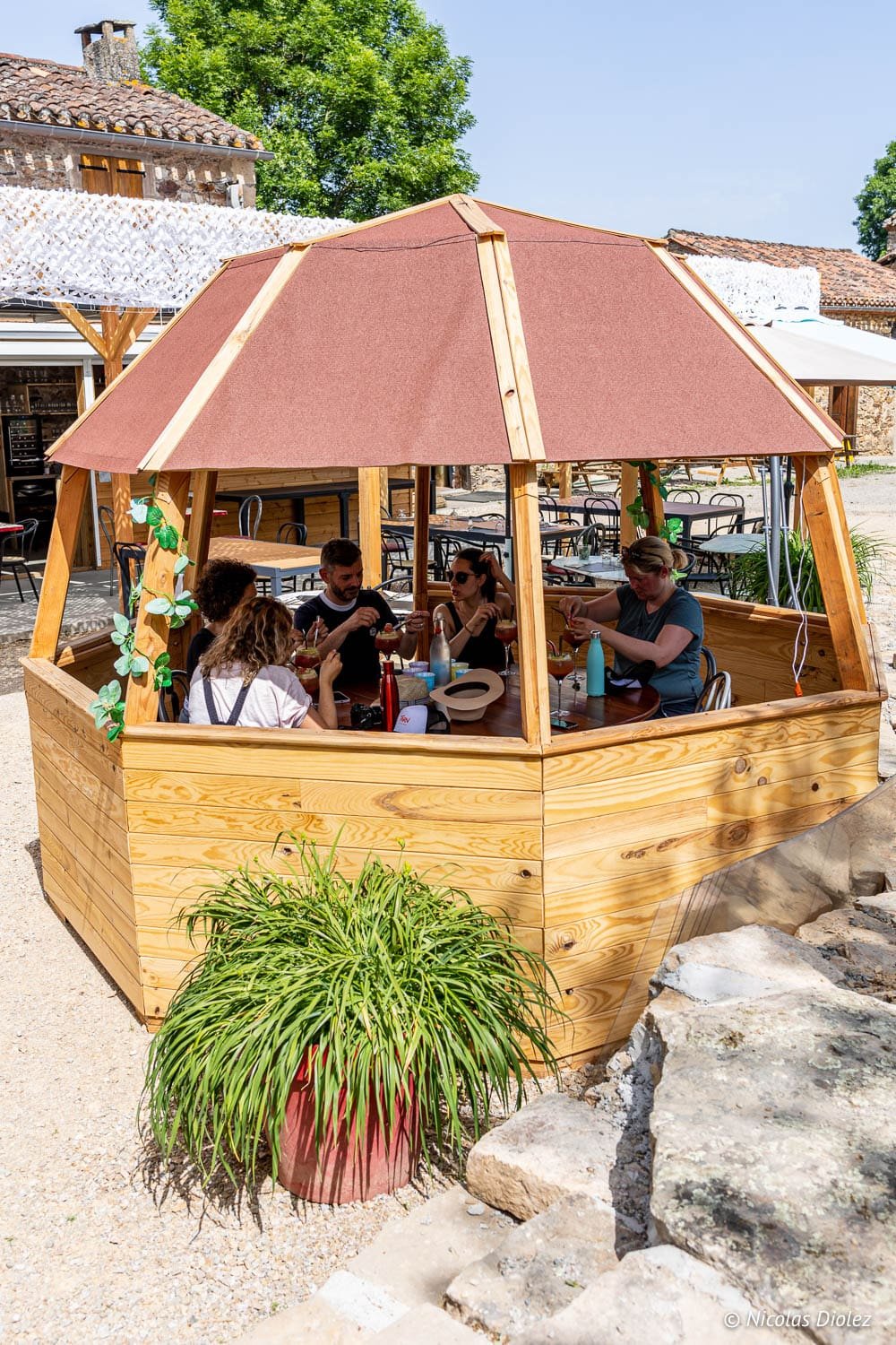 Quatre personnes déjeunent sous un kiosque en bois extérieur.
