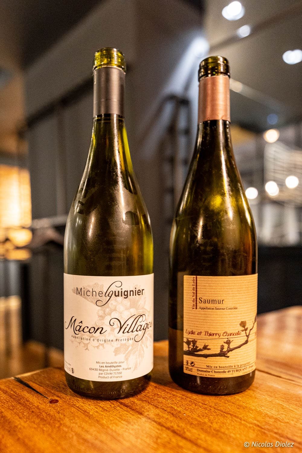 Deux bouteilles de vin blanc sur une table : Mâcon Villages Michel Guignier et Saumur Lydie et Thierry Chancelle.