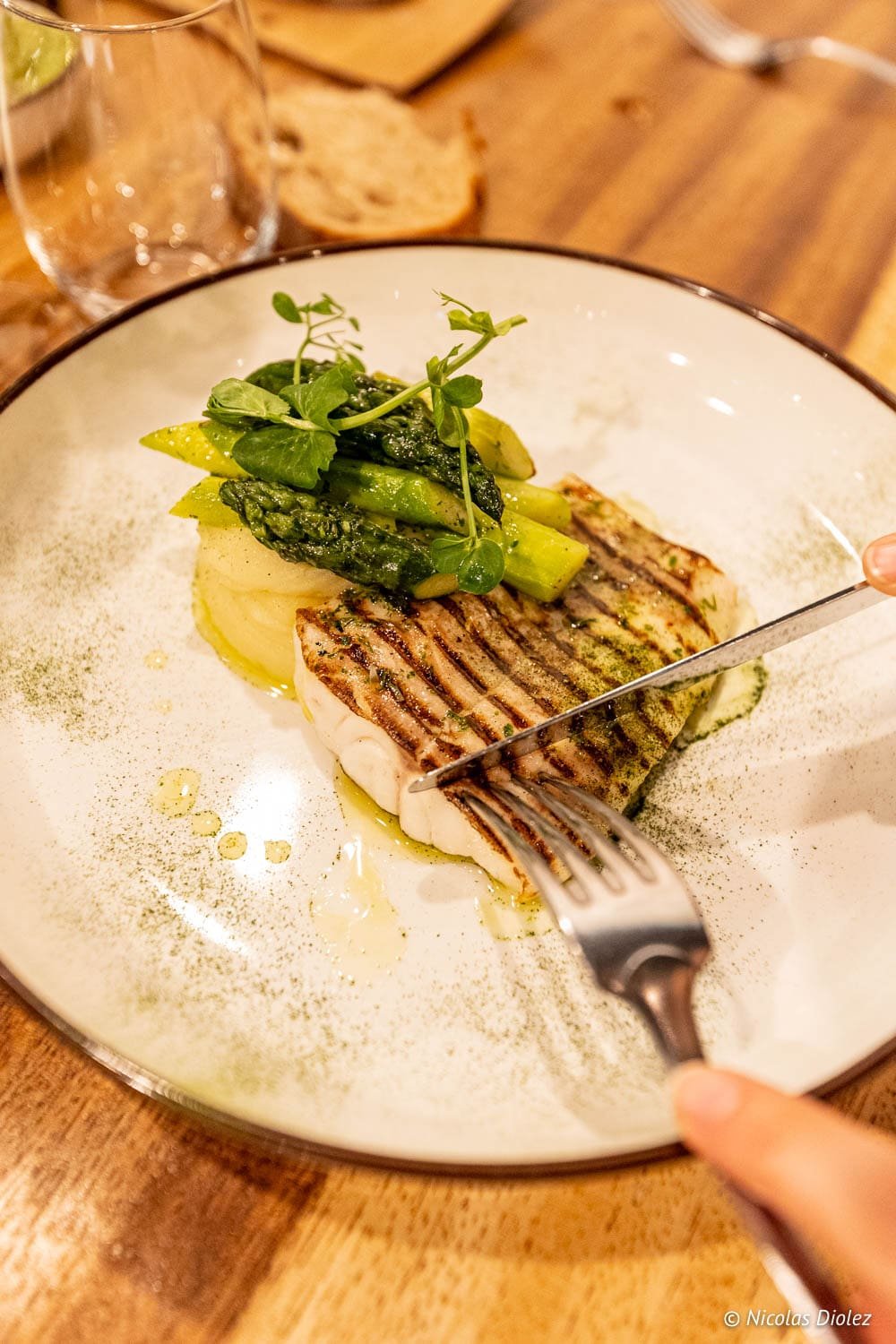 Poisson grillé, asperges vertes et purée coupés à la fourchette et au couteau.