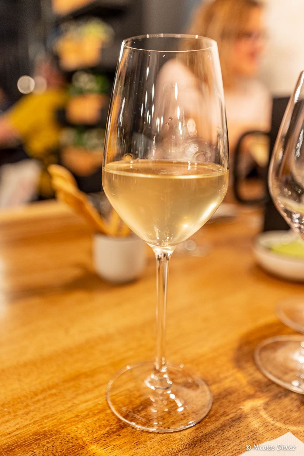 Verre de vin blanc sur table en bois, ambiance restaurant Épicurien Albi.