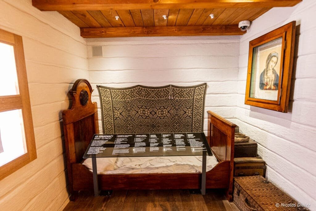 Exposition Musée de l'Émigration Gdynia : lit ancien et objets, panneau "Co Spakować?".