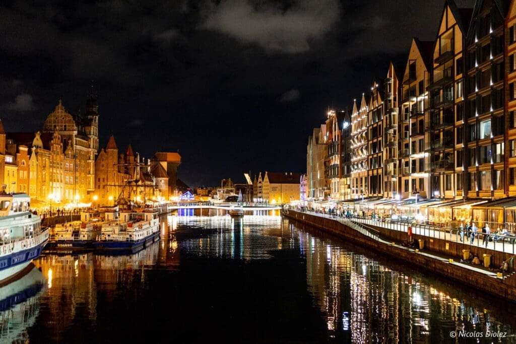 Vue nocturne de la rivière Motława et des maisons illuminées de Gdańsk.