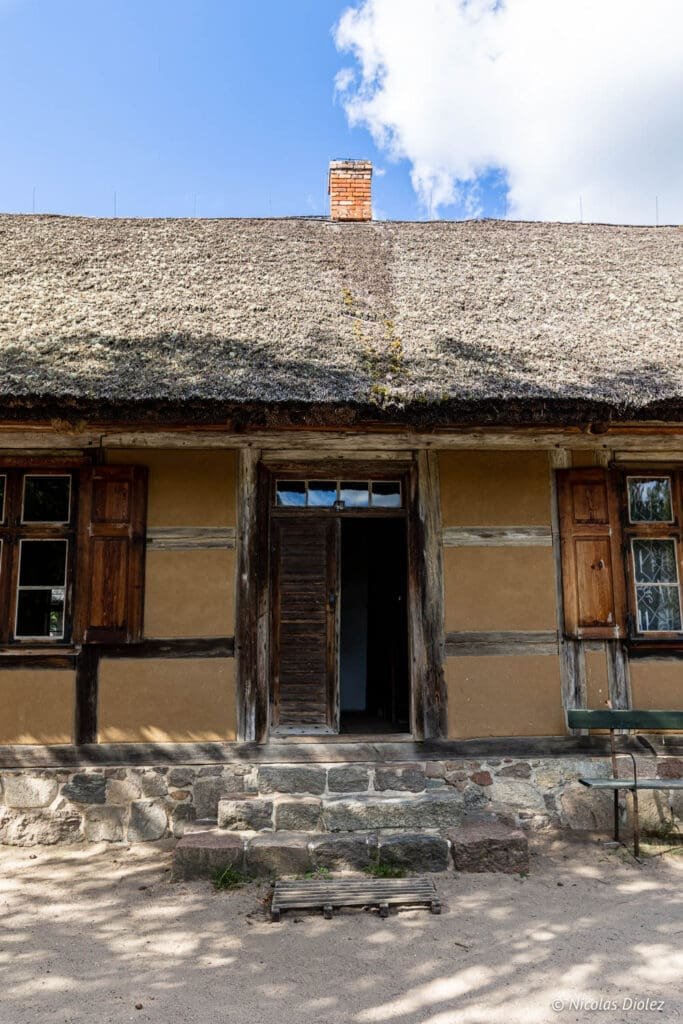Façade d'une maison traditionnelle à colombages avec toit de chaume au Parc ethnographique de Kaszuby.