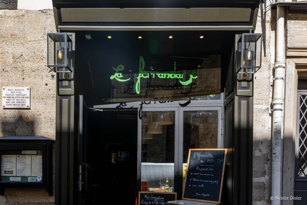 Facciata nera de La Ferrandaise in rue de Vaugirard a Parigi, con l'insegna luminosa verde.
