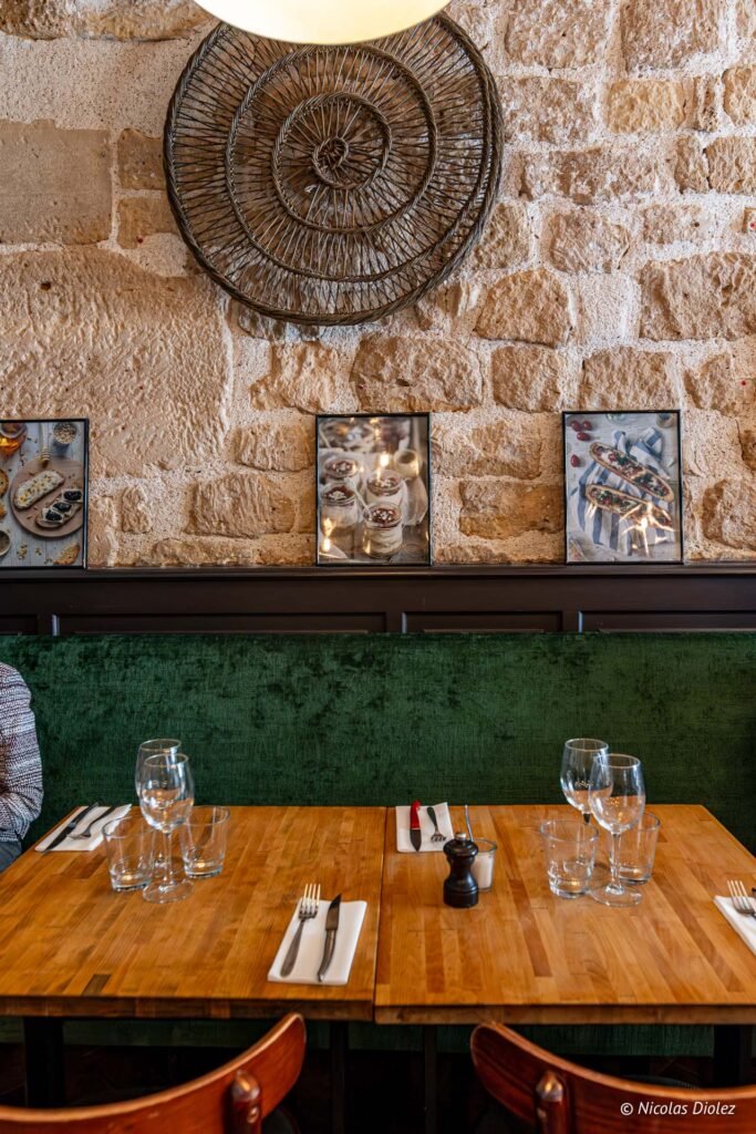 Tavolo apparecchiato davanti al muro di pietra e alla panca verde del bistrot La Ferrandaise a Parigi.