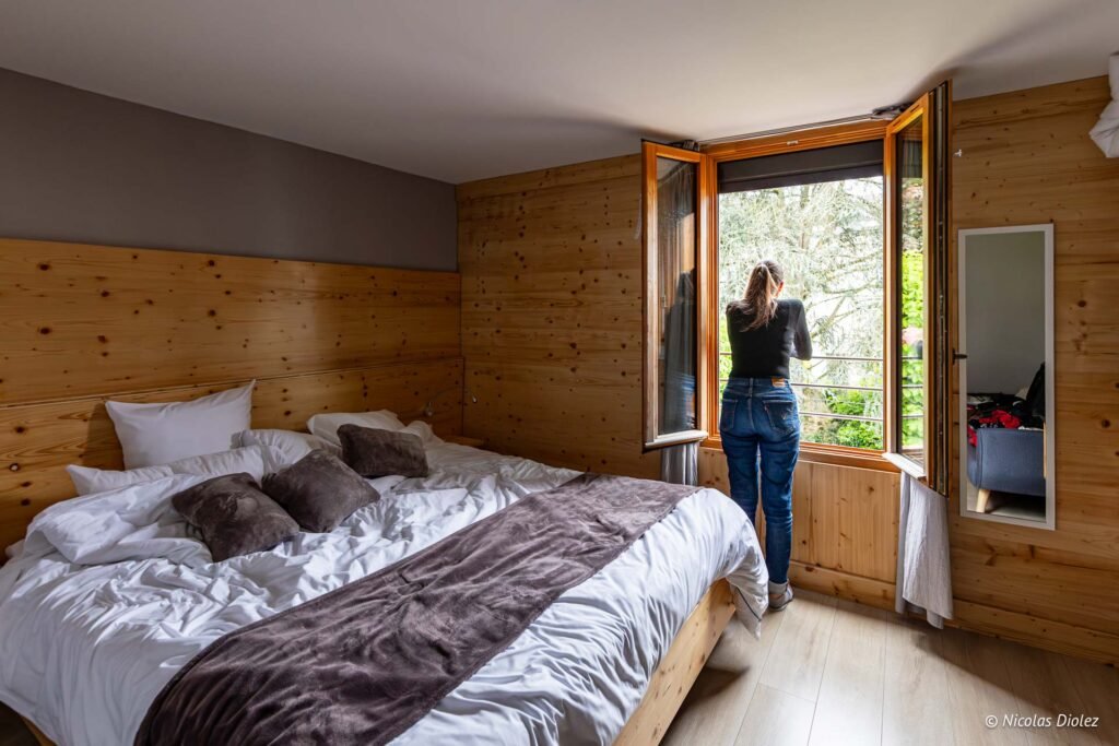 Femme regardant par la fenêtre dans une chambre confortable de l'hôtel Wagram au Mans.
