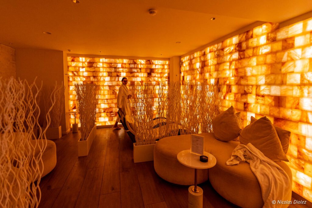 Grotta di sale della spa Paris j'Adore, con pareti di mattoni di sale illuminati e sdraio bianche.