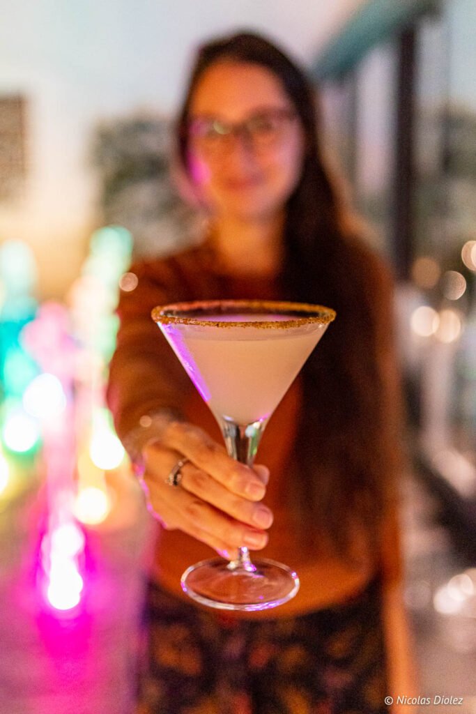 Donna che porge un cocktail in un bicchiere da martini al ristorante dell'hotel Paris j'Adore.
