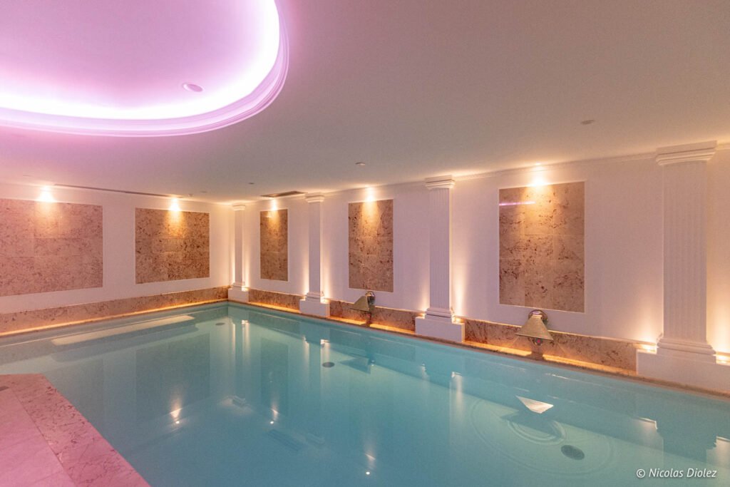 Piscina interna riscaldata della spa dell'hotel Paris j'Adore, illuminata di rosa.