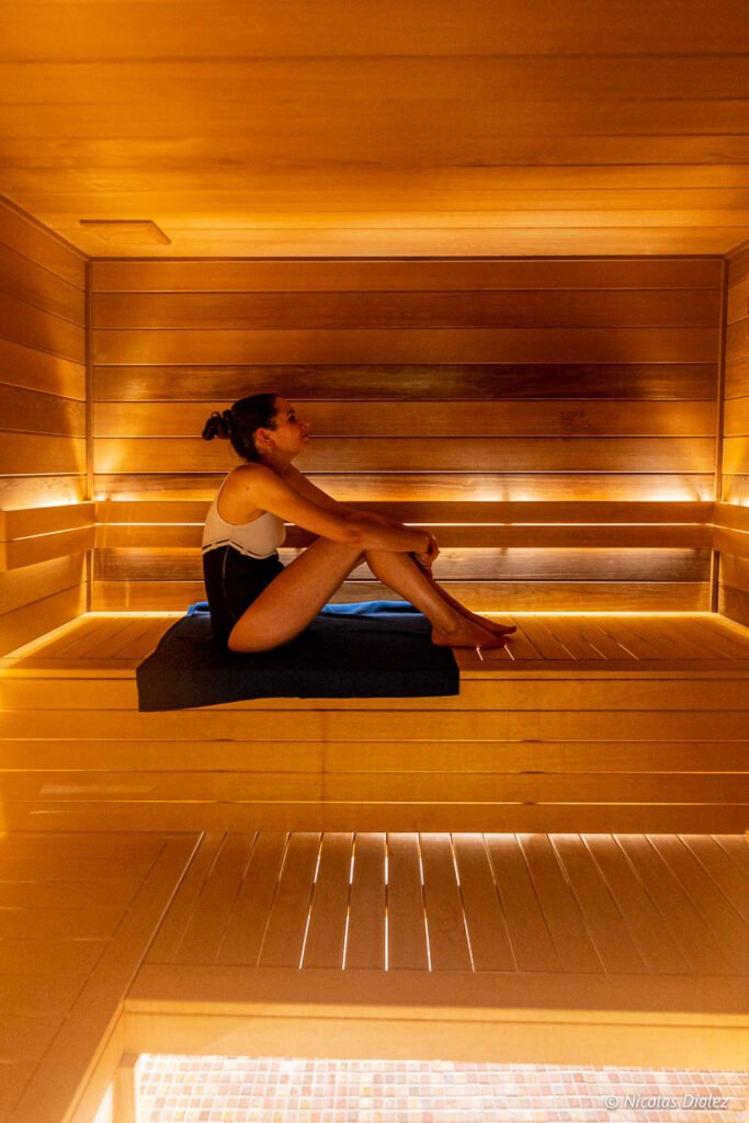 Donna seduta nella sauna in legno illuminata della spa Paris j'Adore.