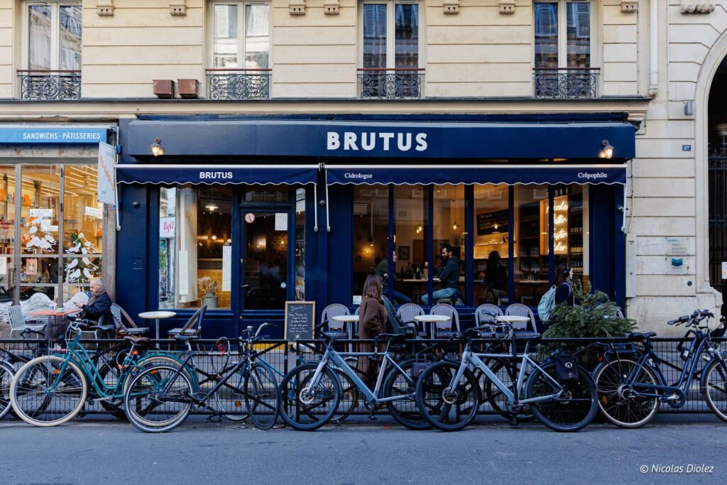 Façade bleue du restaurant Brutus à Paris avec vélos garés et clients à l'intérieur.