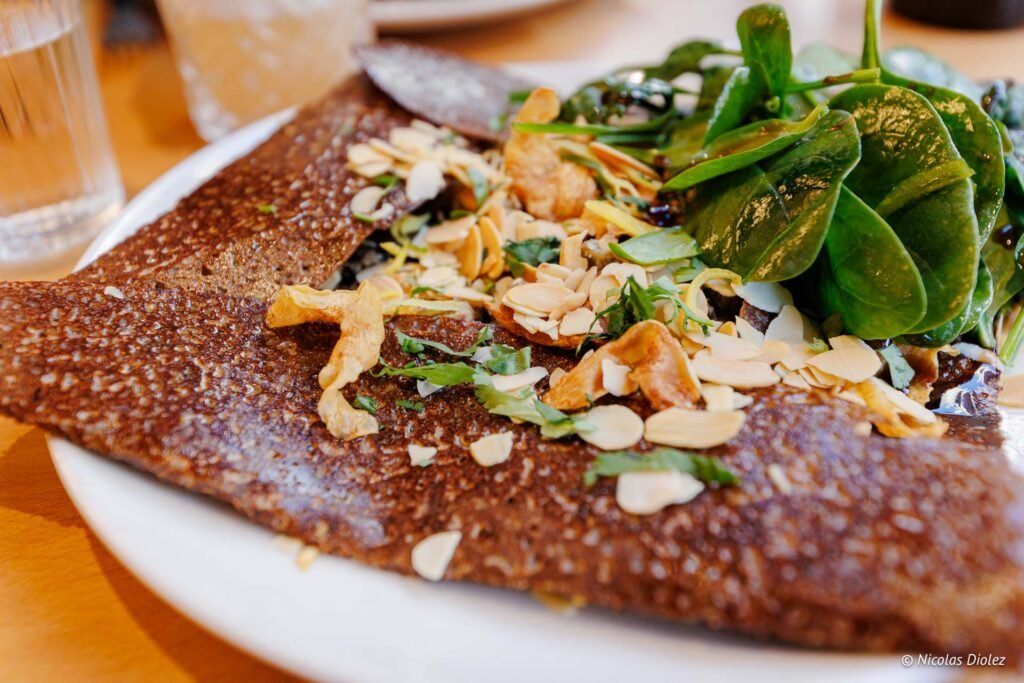 Galette de sarrasin garnie d'amandes effilées, d'épinards frais et d'oignons frits.