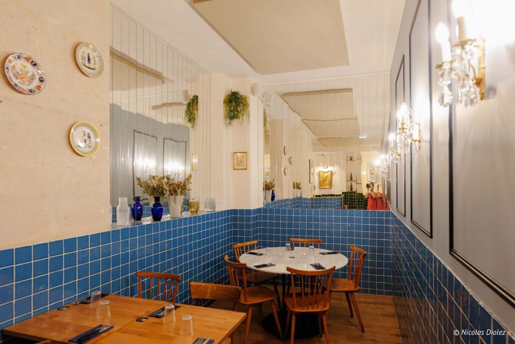 Intérieur restaurant Brutus, murs carrelés bleus, tables en bois et chaises boisées.