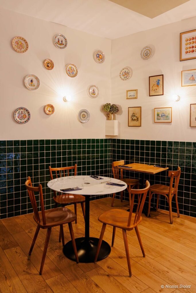 Intérieur de restaurant avec tables, chaises en bois, et assiettes décoratives murales.