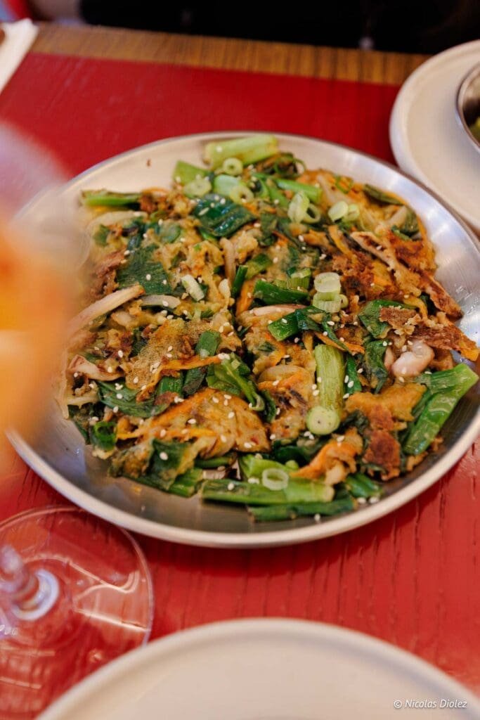Pajeon (galette coréenne aux légumes) de Hallyu Kitchen garni de cébettes.