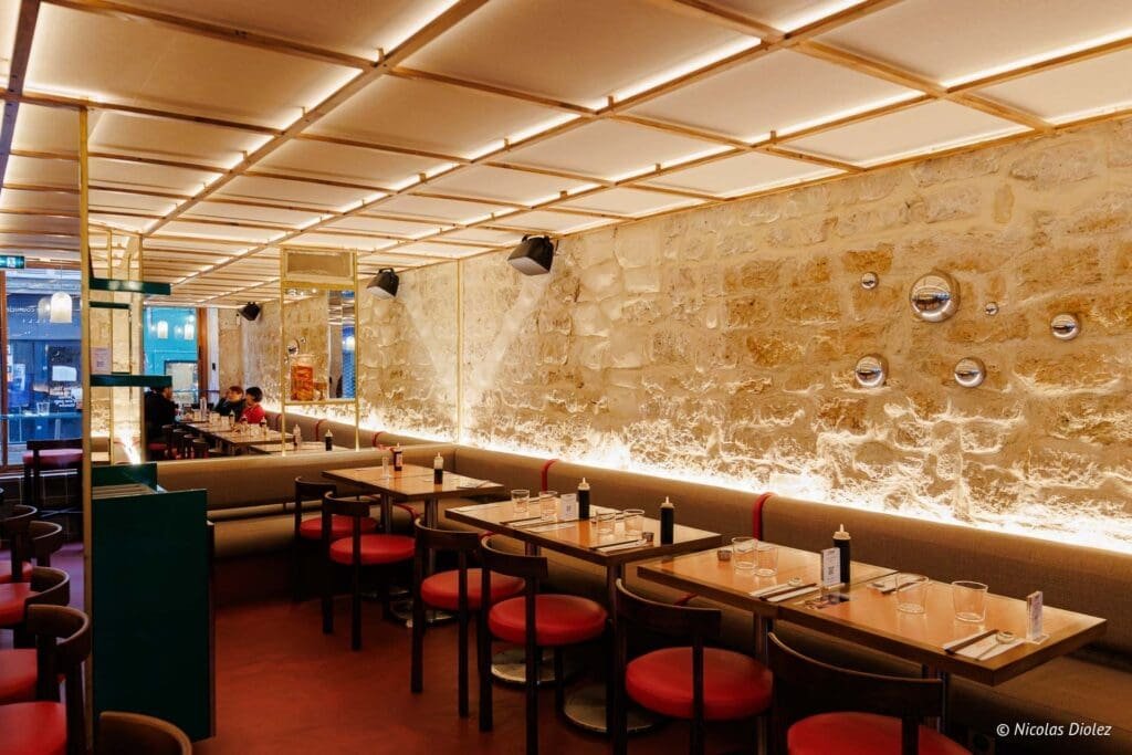 Intérieur restaurant Hallyu Kitchen Paris avec murs en pierre et banquettes.