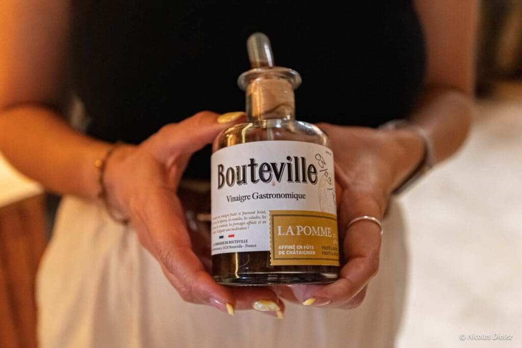 Bouteville Vinaigre Gastronomique Pomme tenu par des mains.