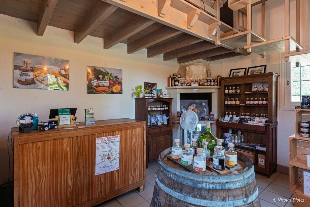 Intérieur boutique La Compagnie de Bouteville avec baril, produits et comptoir en bois.