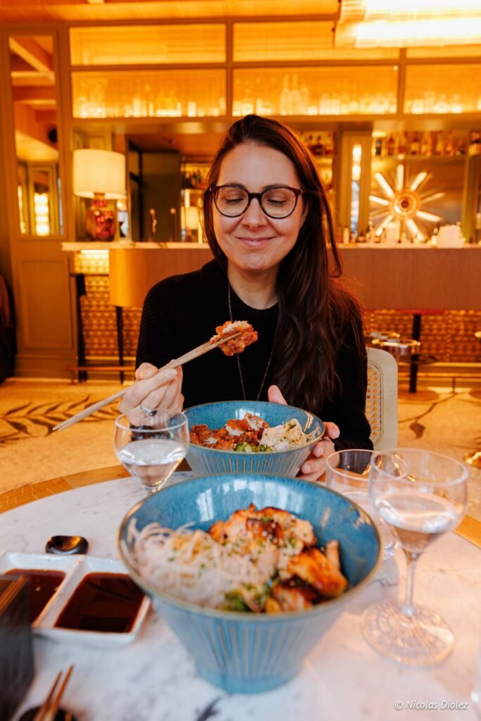Femme mangeant dans un restaurant asiatique avec des bols de nouilles.