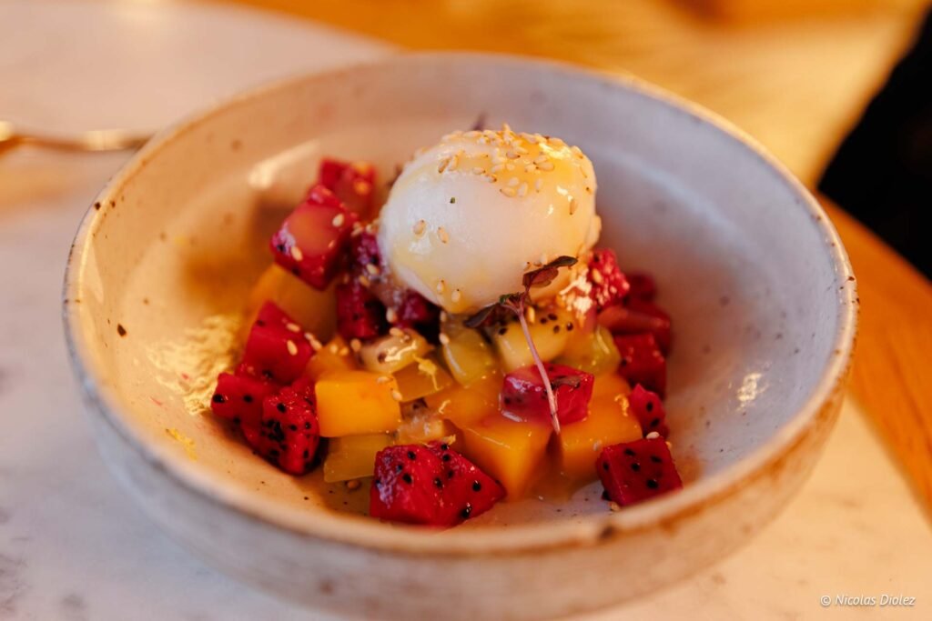 Salade de fruits exotiques avec sorbet, mangue, pitaya et graines de sésame.