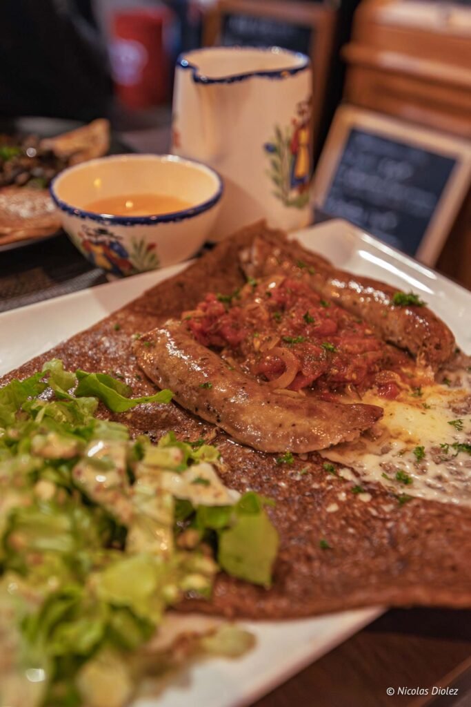 Galette de sarrasin avec saucisses, salade et sauce tomate.