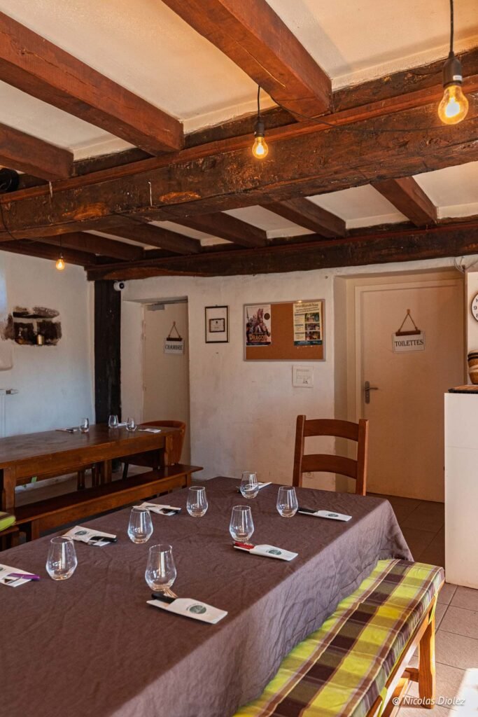 Intérieur rustique Auberge du Val avec tables dressées, poutres apparentes, pancartes CHAMBRE et TOILETTES.
