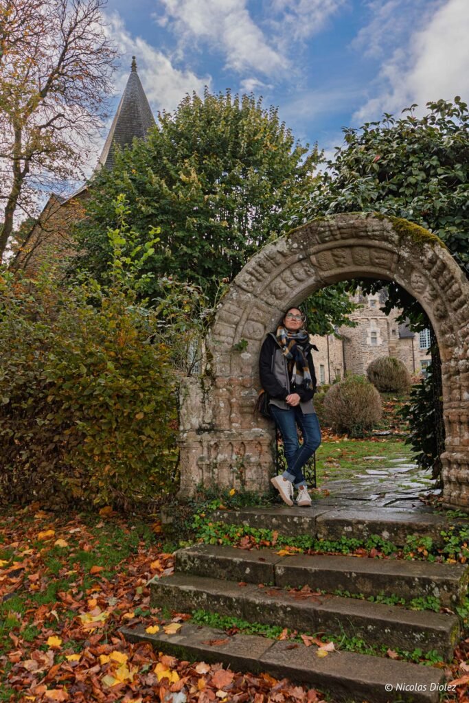Femme appuyée sur une arcade en pierre à Rochefort-en-Terre, automne.