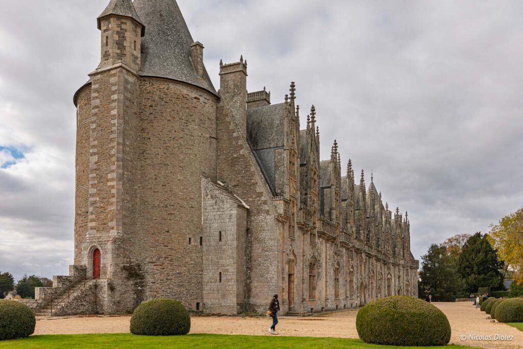 Château de Josselin en Bretagne, façade gothique et tour ronde sous un ciel nuageux.