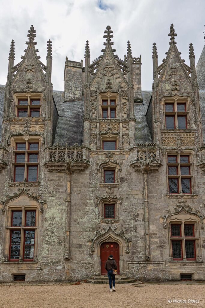 Façade du Château de Josselin richement sculptée avec une personne devant l'entrée.