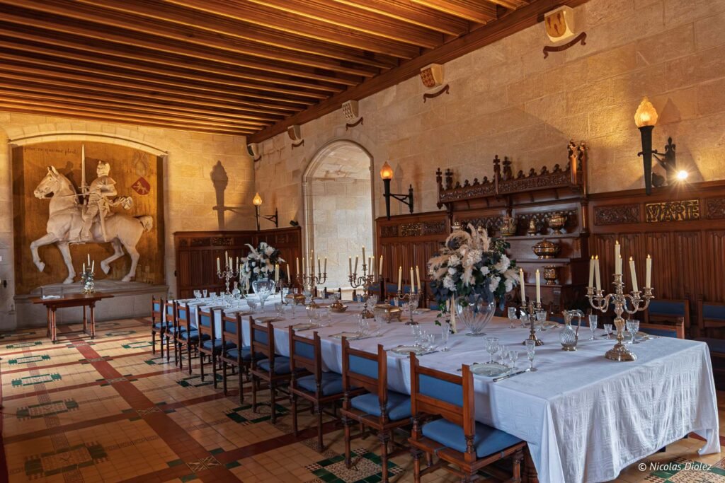 Salle de banquet historique du Château de Josselin avec grande table dressée et sculpture de chevalier.