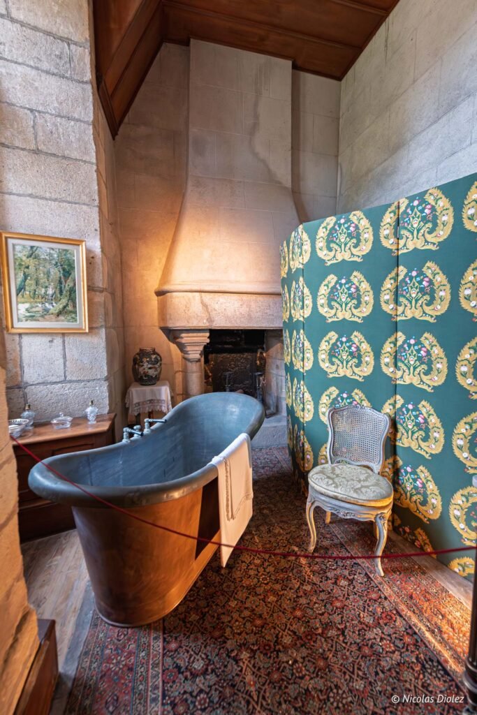 Baignoire ancienne dans une pièce du Château de Josselin avec écran décoratif.