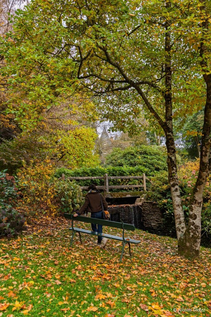 Femme près d'un banc dans le parc d'automne du Château de Josselin.