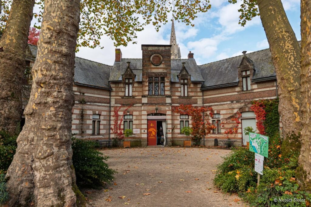 Façade du Musée de Poupées et Jouets Josselin avec feuillage d'automne et flèche d'église.