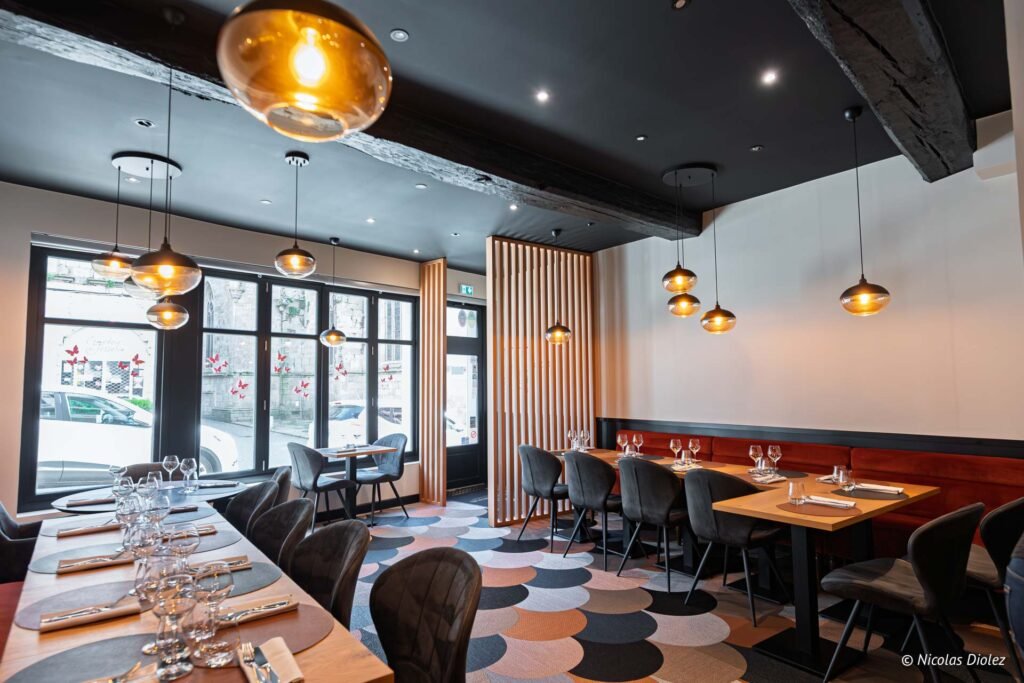 Intérieur restaurant Chez Simon Josselin, tables dressées, luminaires modernes, sol à motifs.