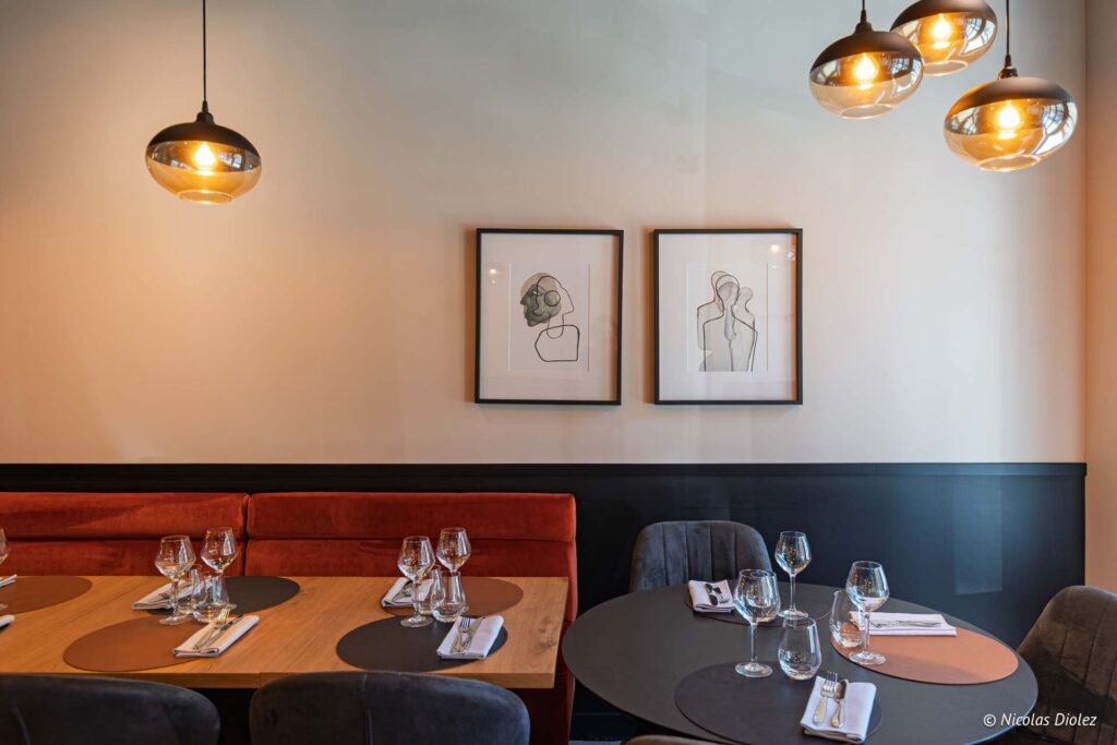 Intérieur restaurant Chez Simon Josselin: tables dressées, banquette rouge et art abstrait.