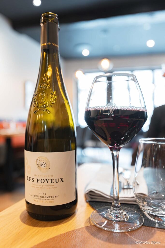 Bouteille et verre de vin rouge Les Poyeux Saumur Champigny 2023.