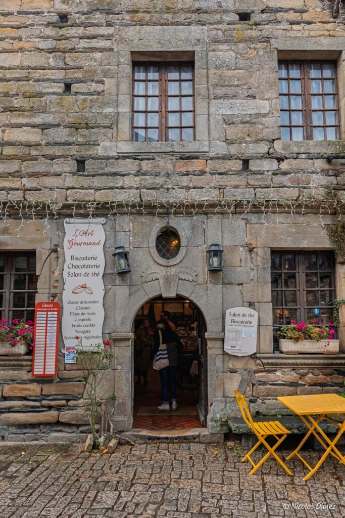 Façade en pierre de Rochefort-en-Terre avec enseigne "L'Art Gourmand" biscuitier chocolatier.