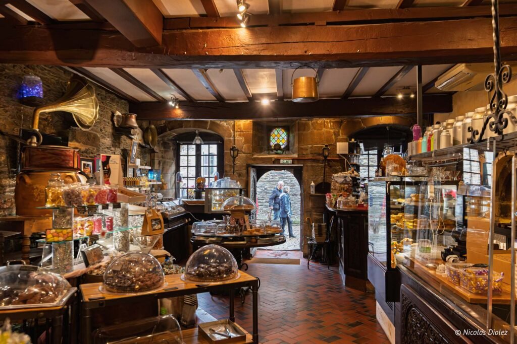 Intérieur rustique d'un commerce de Rochefort-en-Terre avec confiseries et sortie.