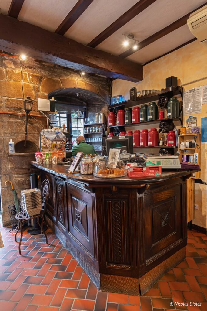 Intérieur commerce Rochefort-en-Terre, comptoir en bois ancien avec boîtes de thé et pâtisseries.