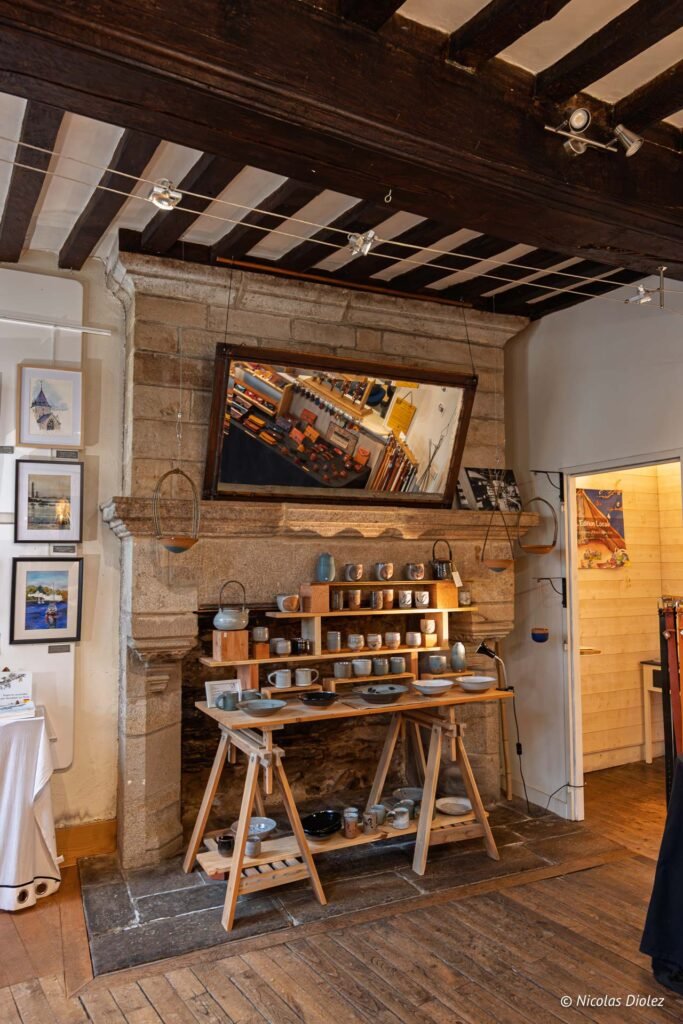 Boutique artisanale Rochefort-en-Terre : poteries exposées sur un tréteau devant une cheminée.