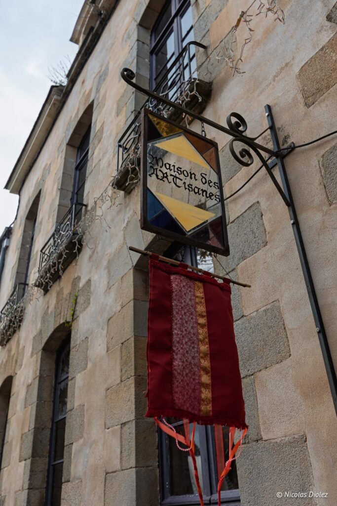 Enseigne "Maison des Artisanes" Rochefort-en-terre sur mur de pierre.